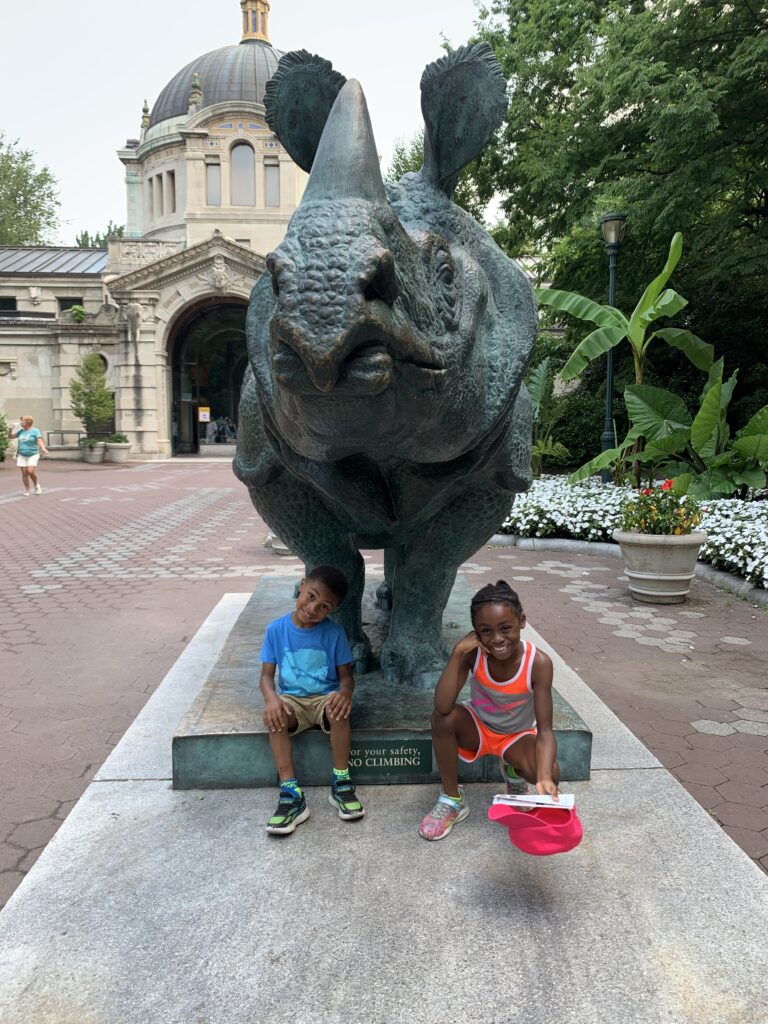 Taking a picture in front of a statue of a Rhino 